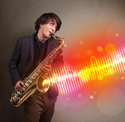 Fototapeta premium Młody mężczyzna grający na saksofonie z kolorowymi falami dźwiękowymi