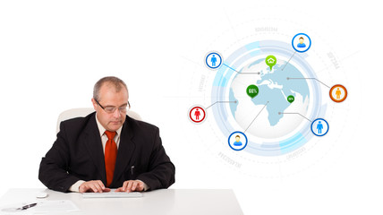 businessman sitting at desk and typing on keyboard with globe an