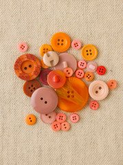 Pile of orange buttons on hessian