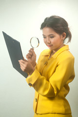 Pretty Asian business woman looking by magnifying glass.