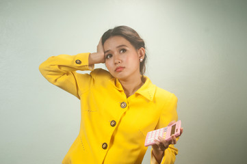 Pretty young Asian woman in yellow suit use calculator.