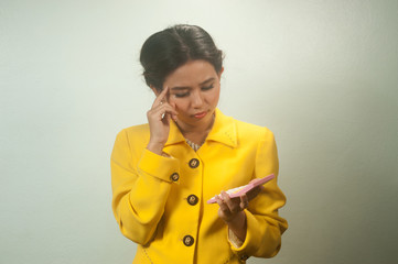 Pretty young Asian woman in yellow suit use calculator.