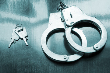 Steel metallic handcuffs with keys on wooden table