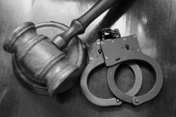 Gavel and handcuffs on wooden background