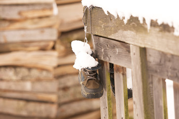 a pair of snow-covered hiking boots hanging on a wooden fence