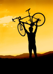 Man holding a road bike over his head with sunset background