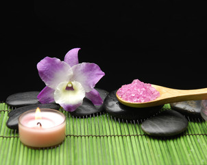 Obraz na płótnie Canvas orchid and candle with zen stone and sea salt in spoon on mat