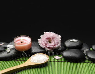 herbal salt in spoon with rose and candle on green mat