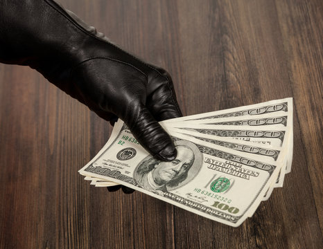 Human hand in black glove holding dollars