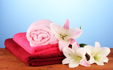 Obraz na płótnie Canvas stack of towels with pink lily on blue background.
