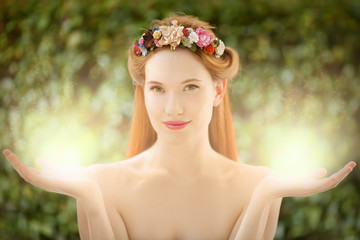 Beautiful fairy woman with glow in hands on natural green backgr