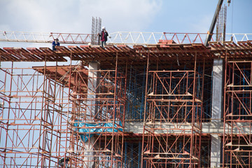 Crane and workers at construction site against blue sky