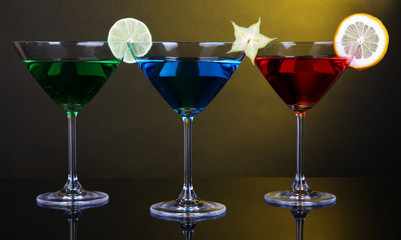 Alcoholic cocktails in martini glasses on dark yellow
