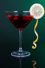 Red cocktail in martini glass on dark green background