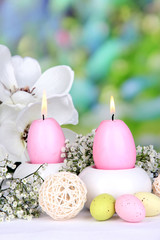 Easter candles with flowers on bright background