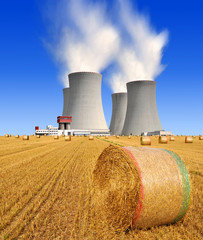 Straw bales on farmland on the background nuclear power plant