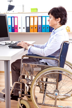 Disabled woman in wheelchair at desk