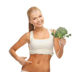 woman pointing at her abs and holding broccoli