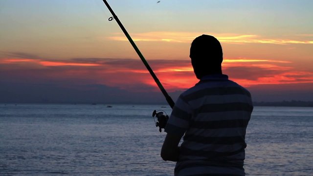 Fisherman throws a fishing tackle against sunset