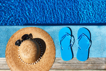 Blue slippers and hat by a swimming pool