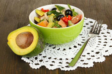 Tasty avocado salad in bowl  on wooden table close-up