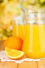 Full glass and jug of orange juice and oranges