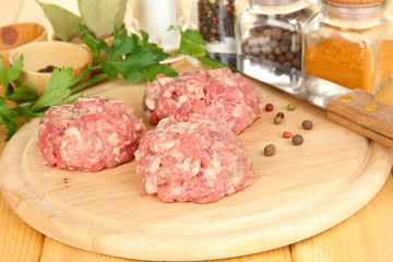 Raw meatballs with spices on wooden table