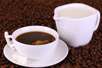 A cup of strong coffee and sweet cream on coffee beans close-up