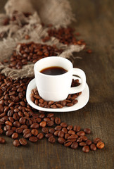 Cup of coffee and coffee beans on wooden background