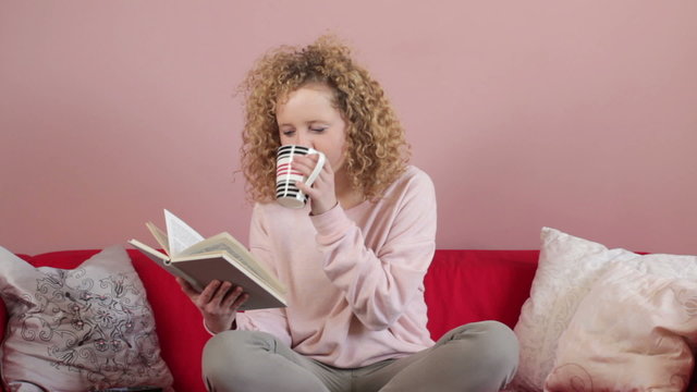 Young woman reading book and drinking tea