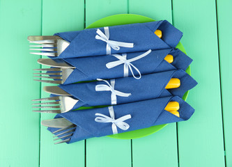 Forks and knives wrapped in blue paper napkins,