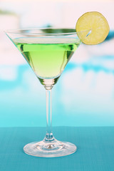 Green cocktail with lime on table on bright background