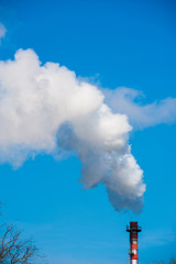 Smoke from industrial chimney on blue sky.