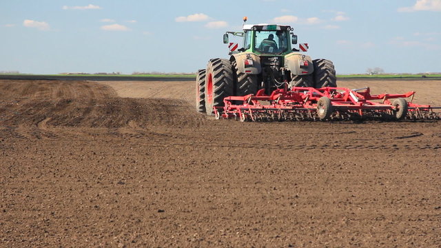 Large tractor cultivating field, preparing for sowing