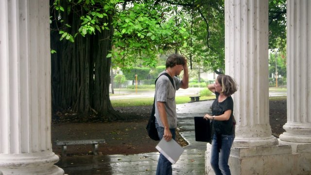 Students smiling, man and woman running in the rain during storm
