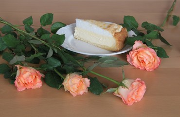 Obraz na płótnie Canvas Ein Stück Torte auf dem Teller zwischen Rosen