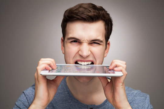 Man biting digital tablet