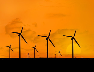 Several wind turbines with a sunset in line