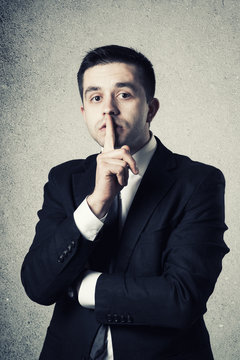 Business man with finger on lips asking for silence