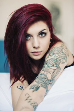 Sensual portrait of beautiful girl with tattoo lying on bed.
