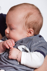 Baby in arm of mother. Closeup. Studio shot.