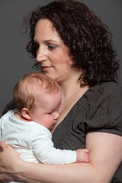 Baby daughter in the arms of mom. Studio shot.