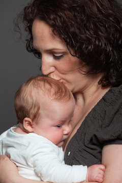 Baby daughter in the arms of mom. Studio shot.