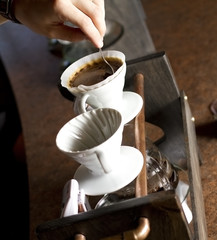 an employee stirs filtering water of a single cup of coffee