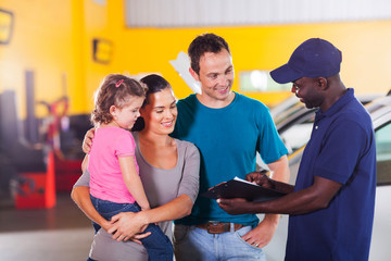 friendly auto mechanic talking to young family