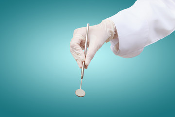Closeup of dentist hand taking mirror from on of dental tools.