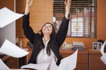 Happy businesswoman tossing papers in the air