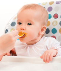 Mom feeds funny baby from  spoon