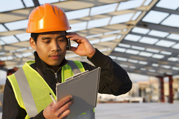 Engineer construction talking mobile phone under new building