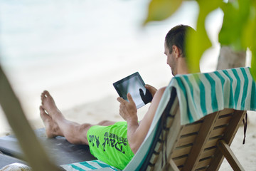man ralaxing and use tablet at beach